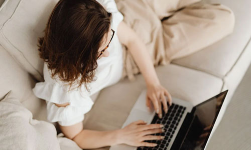 A-Woman-on-the-Couch-Typing-on-a-Laptop